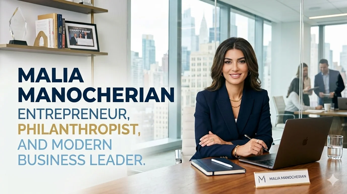 Malia Manocherian, entrepreneur, philanthropist, and modern business leader, seated confidently at a corporate office desk with a laptop, notebook, and city skyline view in the background.