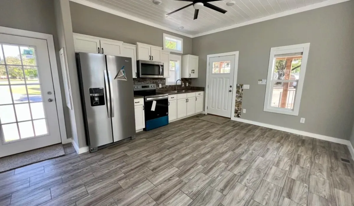 Interior of a mobile home kitchen featuring a white shiplap-style mobile home ceiling with a black modern ceiling fan and recessed lighting.