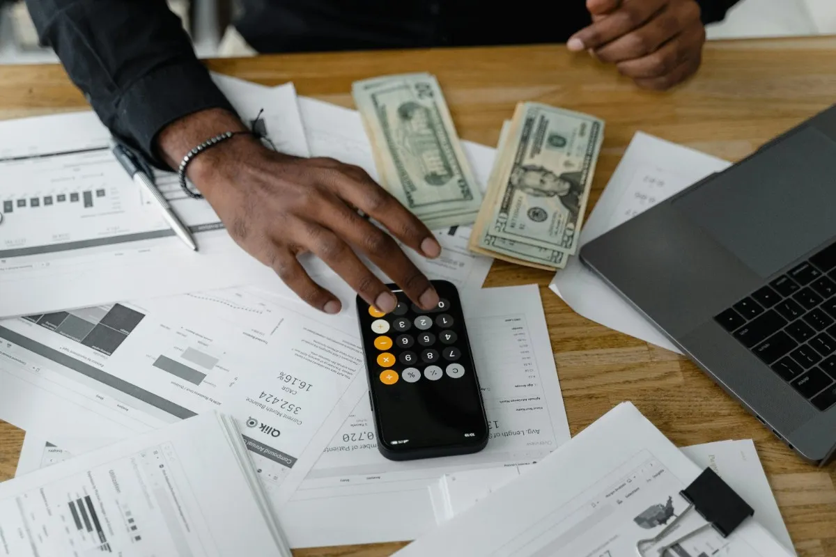 A financial advisor using the GoMyFinance Invest methodology to calculate earnings, surrounded by US currency, data reports, and a laptop for comprehensive investment planning.