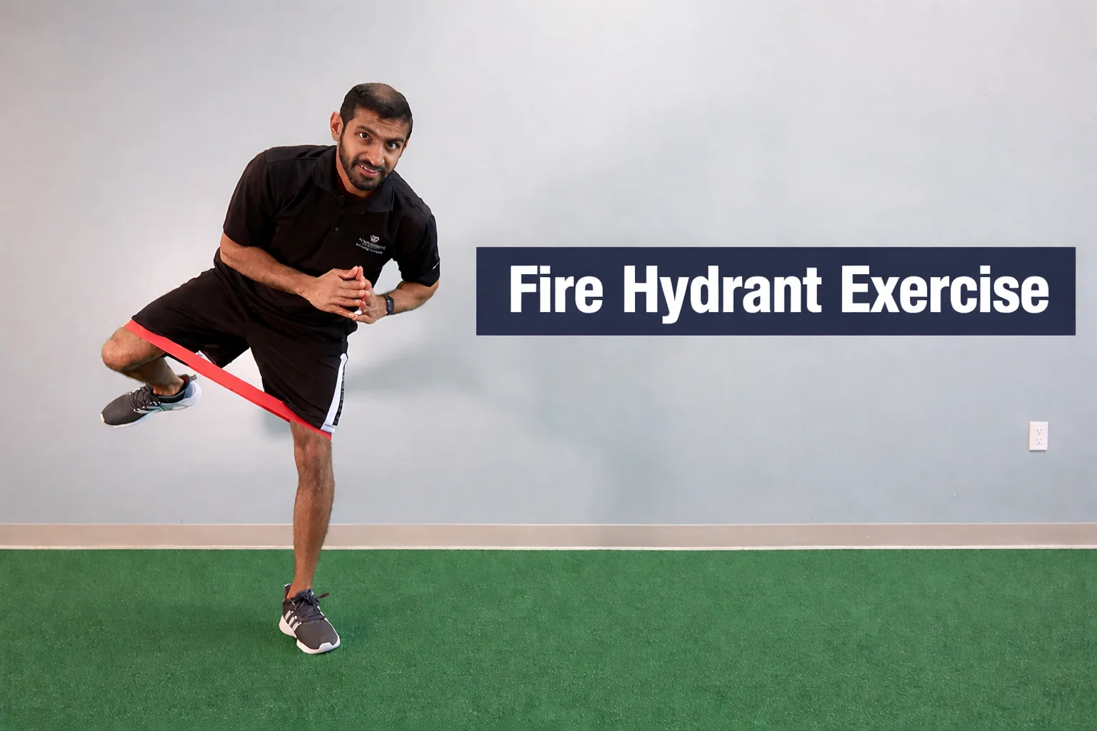 A fitness trainer demonstrating a standing fire hydrant exercise variation with a red resistance band around his ankles, lifting one leg laterally while balancing on one foot in a gym setting.
