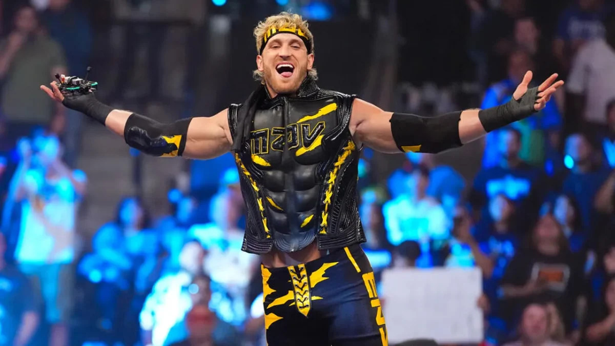 Logan Paul making a dramatic arms-wide entrance in his black and yellow WWE ring gear and matching headband before a packed arena crowd, representing the WWE career that has significantly boosted Logan Paul net worth through entertainment contracts and pay-per-view events.