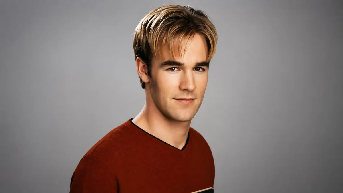 A young Ryan Reynolds in a promotional headshot wearing a dark red sweater against a grey studio background, reflecting his early acting career before building his impressive Ryan Reynolds net worth.