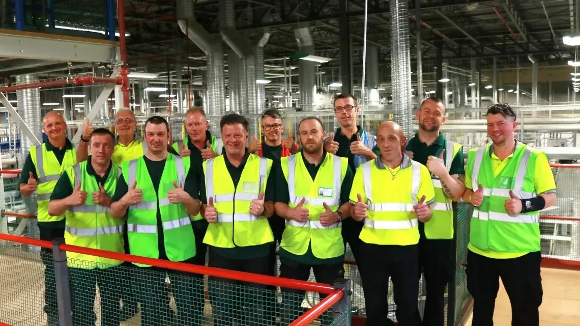 Wren Kitchens Chapter 7 factory team wearing high-visibility vests giving thumbs up inside an industrial production facility