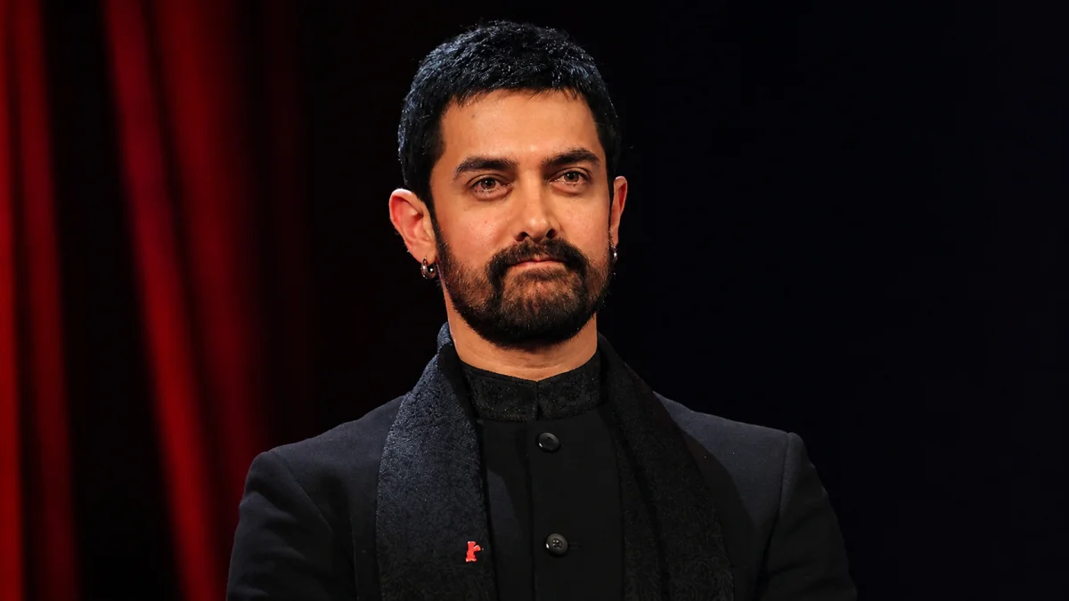 Aamir Khan net worth wearing a navy blazer over a black Nehru-collar outfit with a red Berlinale bear pin on his lapel at the Berlin International Film Festival