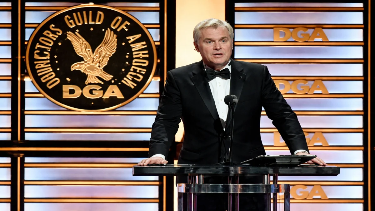 Director Christopher Nolan speaking at the Directors Guild of America (DGA) podium, a testament to the industry prestige that has significantly built the Christopher Nolan net worth.