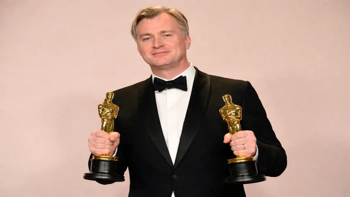 Director Christopher Nolan holding two Oscar statuettes, a visual representation of the elite industry success that has significantly grown the Christopher Nolan net worth.