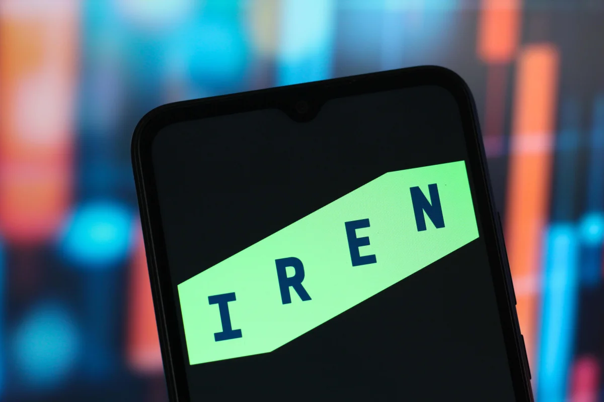 IREN stock logo displayed on a smartphone screen with a glowing green brand mark against a blurred colorful financial chart background