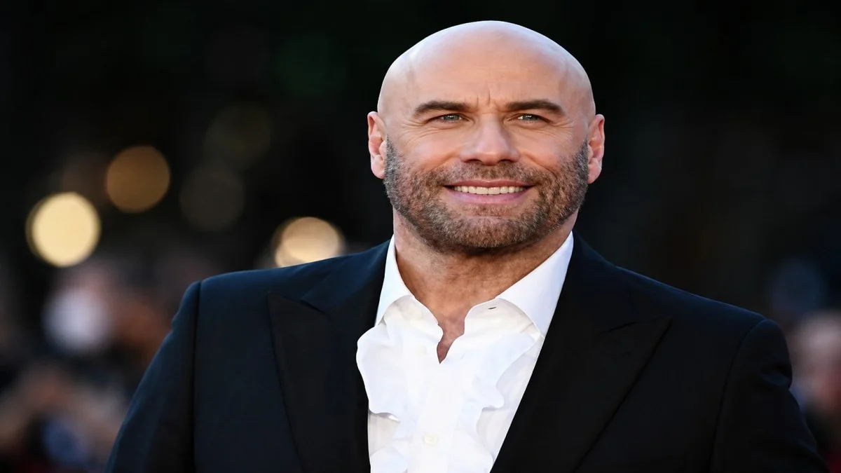 John Travolta smiling in a black suit during a red carpet celebrity event portrait image