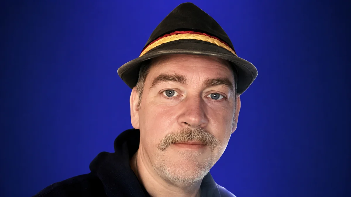 Kevin Knasel Net Worth portrait image with blue background and stylish hat looking at camera