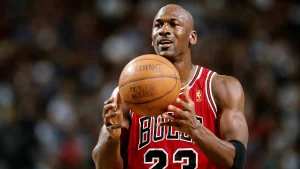 Michael Jordan holding a basketball in a Chicago Bulls jersey during an NBA game – Michael Jordan Net Worth and basketball legacy image