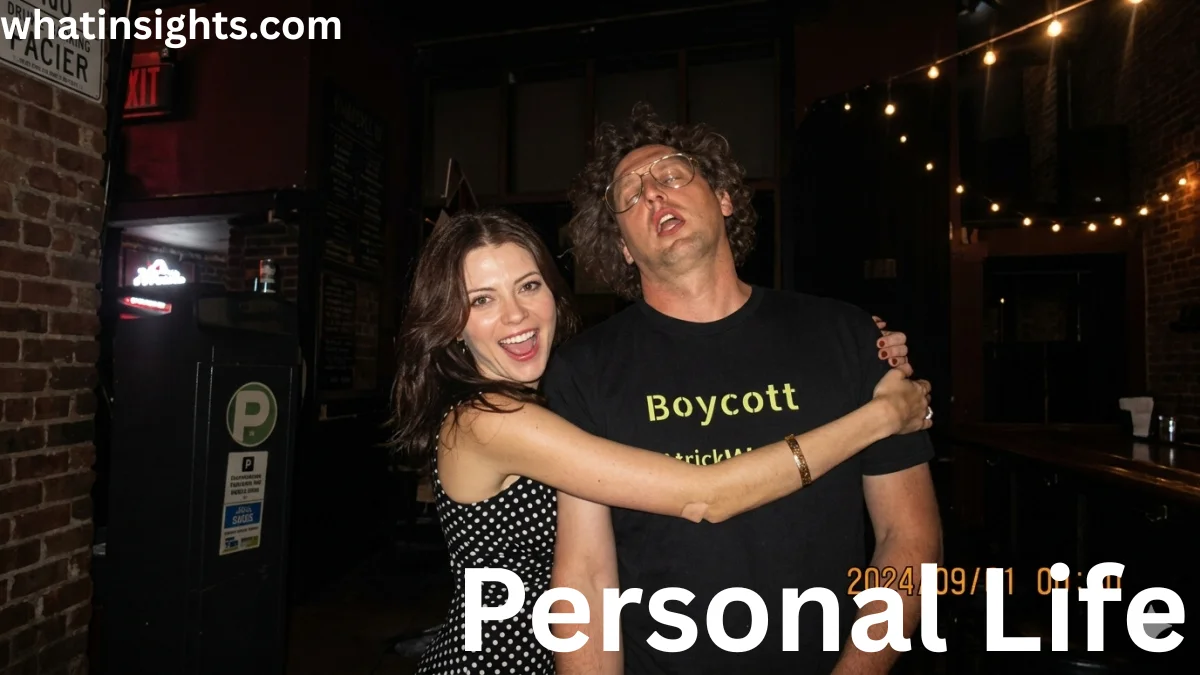 A woman in a polka dot dress smiling and hugging a man with glasses and curly hair who is wearing a black "Boycott" t-shirt, featured in a discussion about Patrick W Cutler Net Worth.