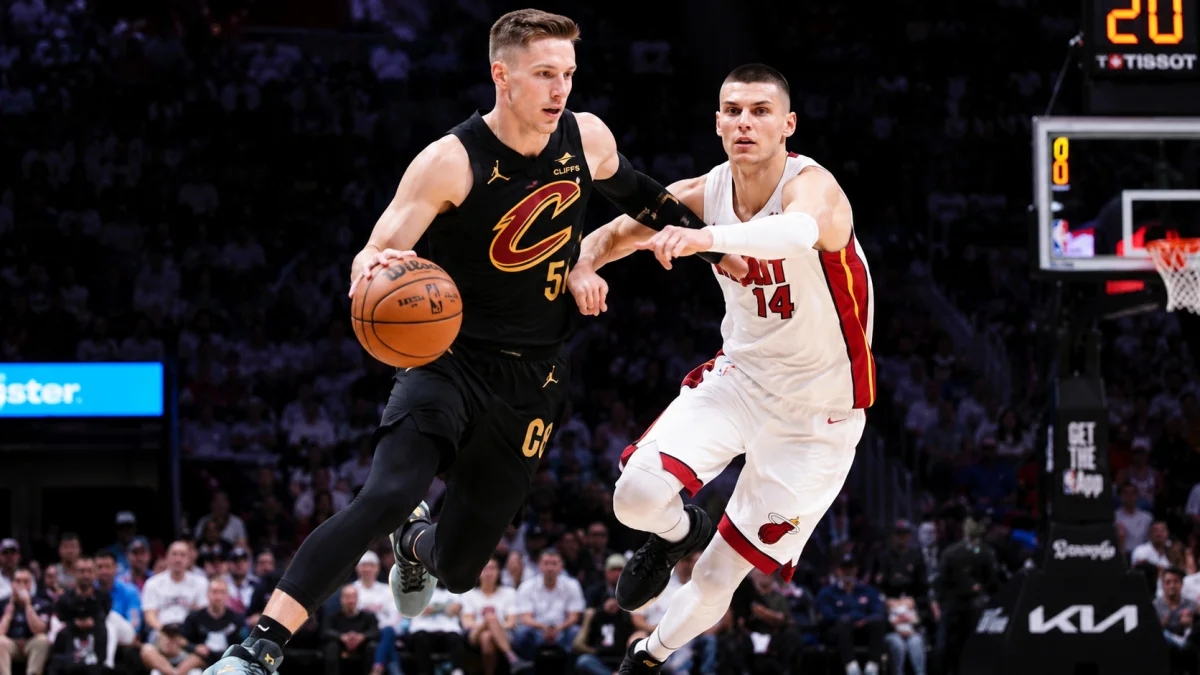 Sam Merrill dribbling past a defender during a fast-paced Cleveland Cavaliers NBA game inside a packed basketball arena.
