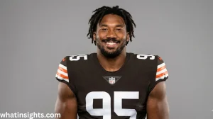A professional studio headshot of NFL player Myles Garrett smiling in his brown and orange Cleveland Browns uniform jersey with number 95 against a solid grey background.
