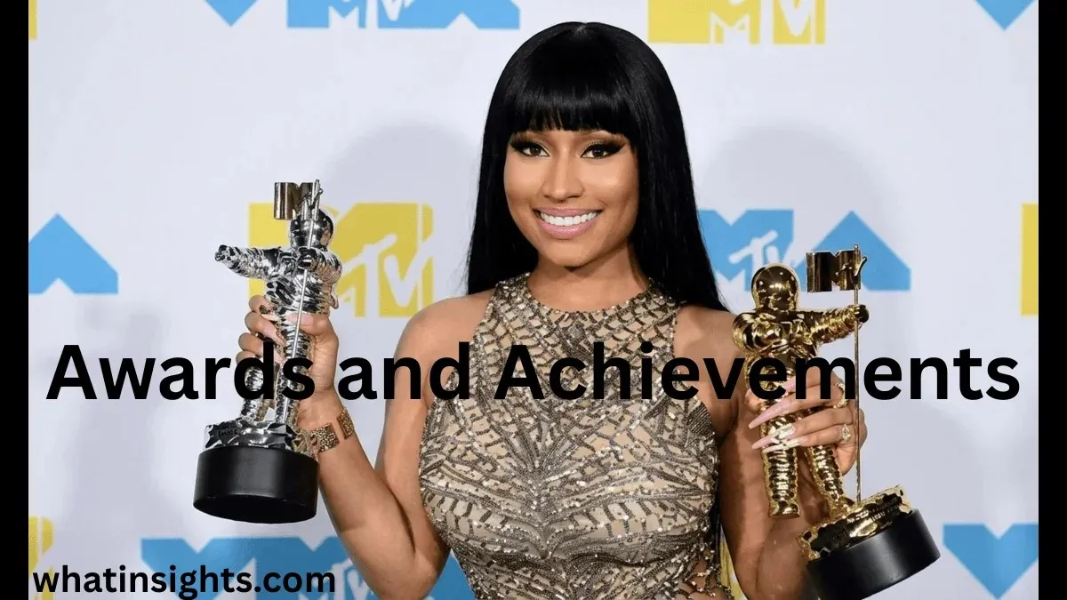 Nicki Minaj smiling while holding two MTV Video Music Award Moonman trophies, showcasing the industry accolades that heavily contribute to the overall Nicki Minaj Net Worth.